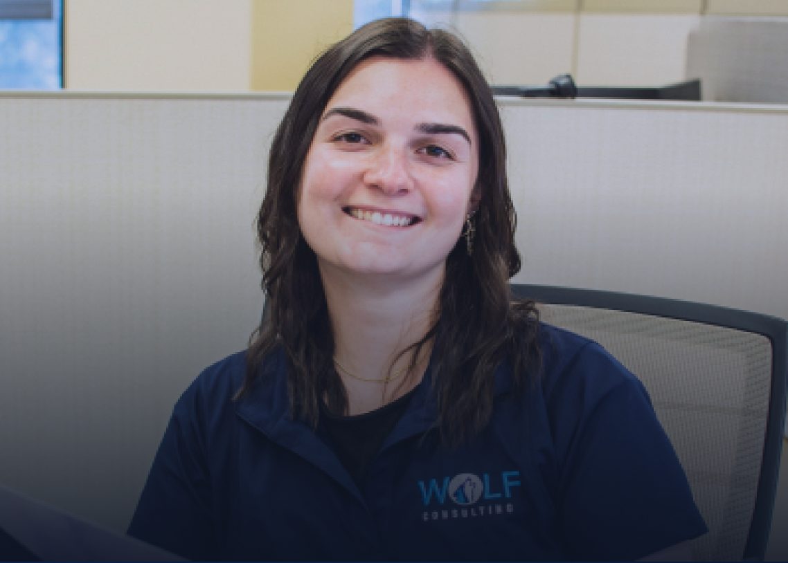 A smiling Wolf Consulting employee seated at her desk