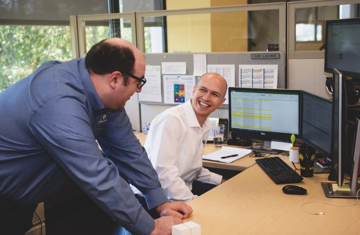 Two Wolf Consulting engineers sharing a laugh at a support desk